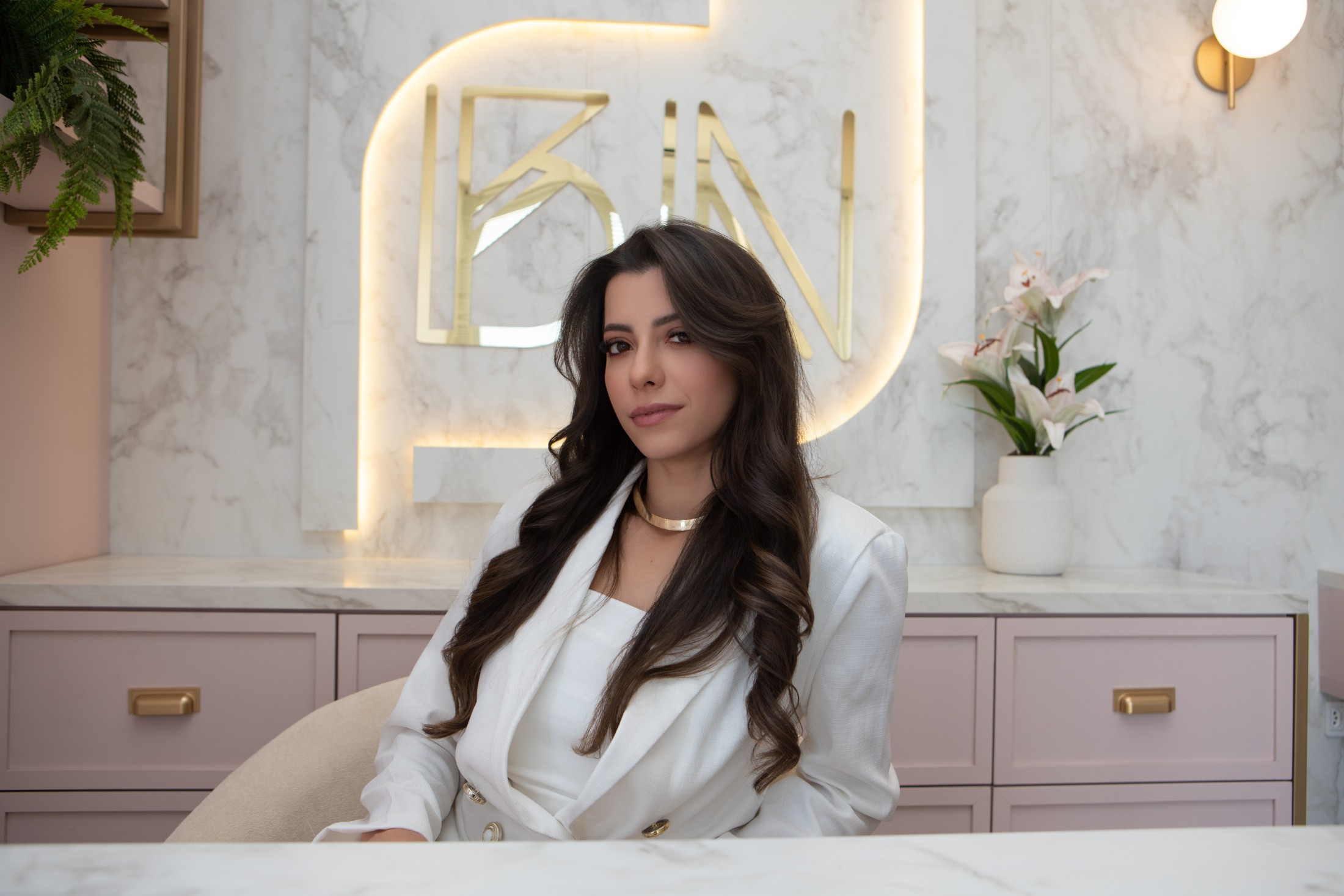 Bruna Nycole na BN Clinic, sob o letreiro BN em dourado iluminado